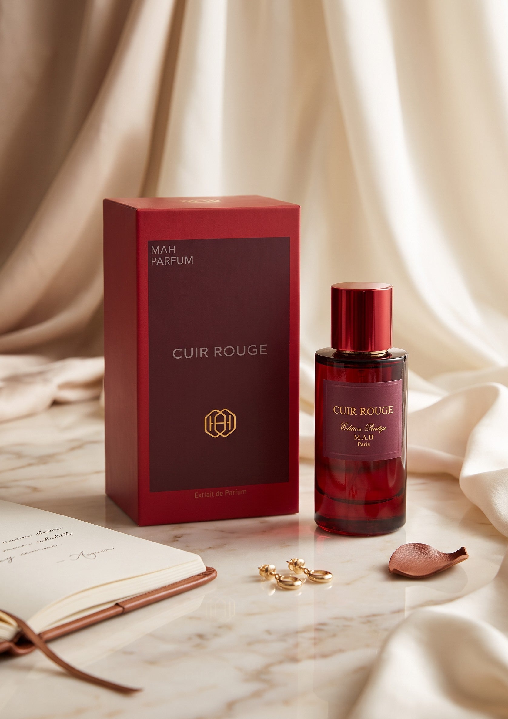 Flacon de parfum Cuir Rouge de PDS SHOP avec sa boîte rouge élégante sur un fond de tissu drapé et un carnet