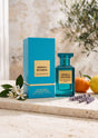 Flacon et boîte de parfum PDS SHOP Neroli Riviera 80ml, bleu turquoise, entourés de fleurs d'oranger et d'agrumes.