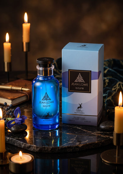 Flacon de parfum bleu Azure Jean Lowe de Maison Alhambra avec sa boîte, posé sur une table sombre avec des bougies.