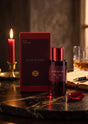 Flacon de parfum Cuir Rouge de MAH et son coffret rouge sur une table en marbre avec une bougie, PDS SHOP